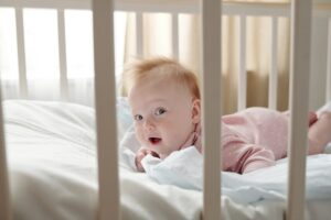 Happy baby girl looking at camera while creeping in crib
