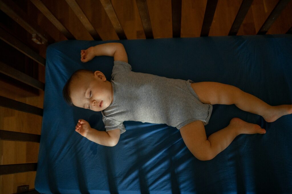 The baby sleeps in a crib on a blue sheet