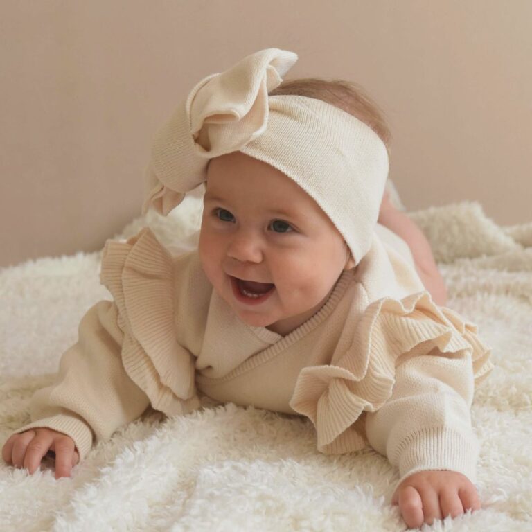 Omslagsbody med volang i bomull, ivory farge – strikket babybody til nyfødt og hentesett