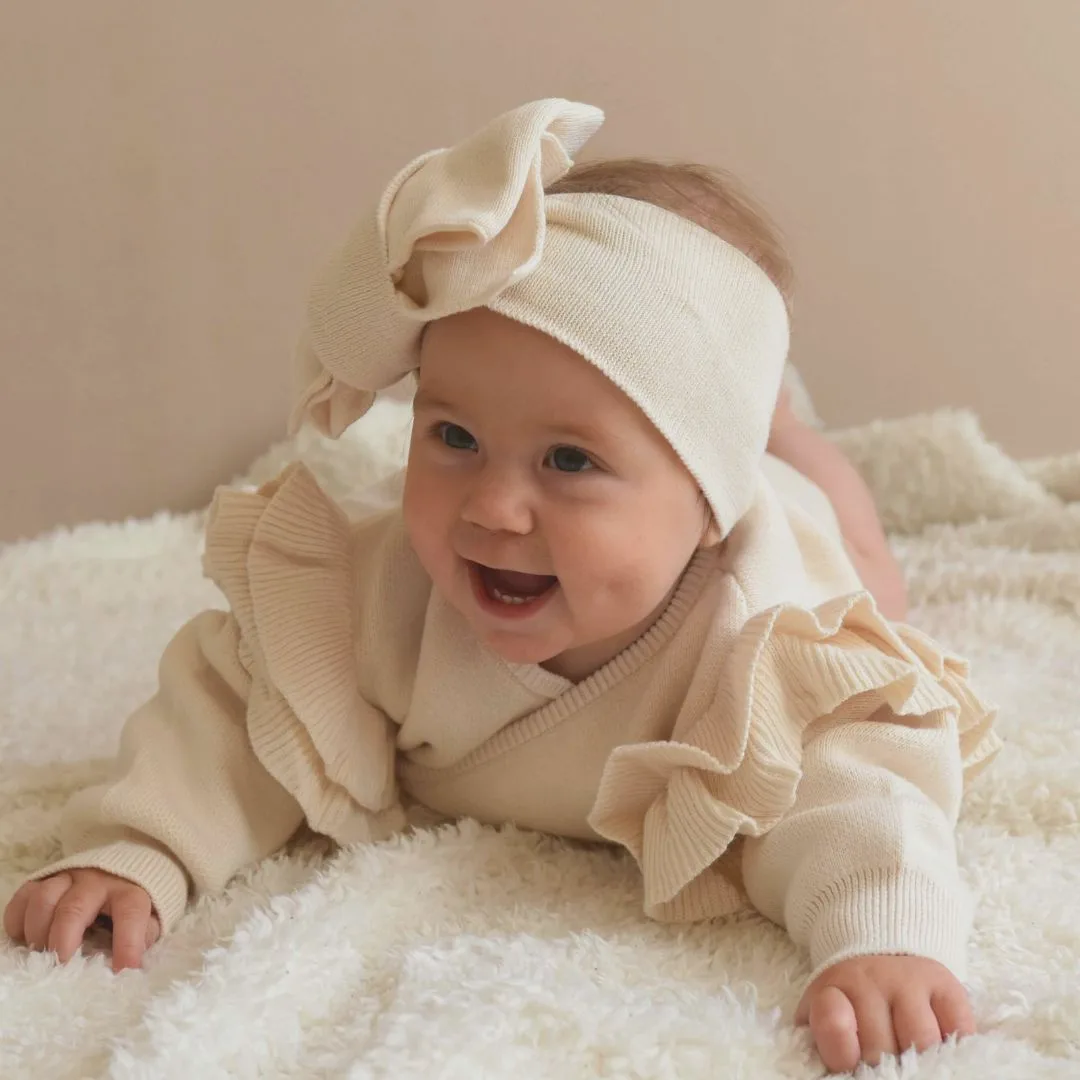 Omslagsbody med volang i bomull, ivory farge – strikket babybody til nyfødt og hentesett